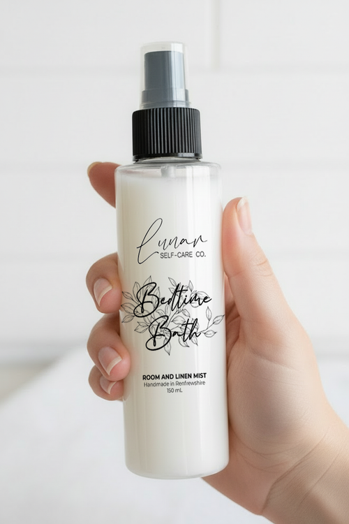 Hand holding a bottle of 'Bedtime Bath' room and linen mist with a white background